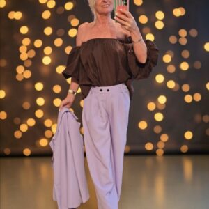 vrouw met paarse broek en bruine ofshoulder top