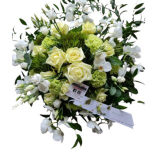 Rouwbloemstuk in witte en groene kleurstelling, voorzien van orchideeën.
